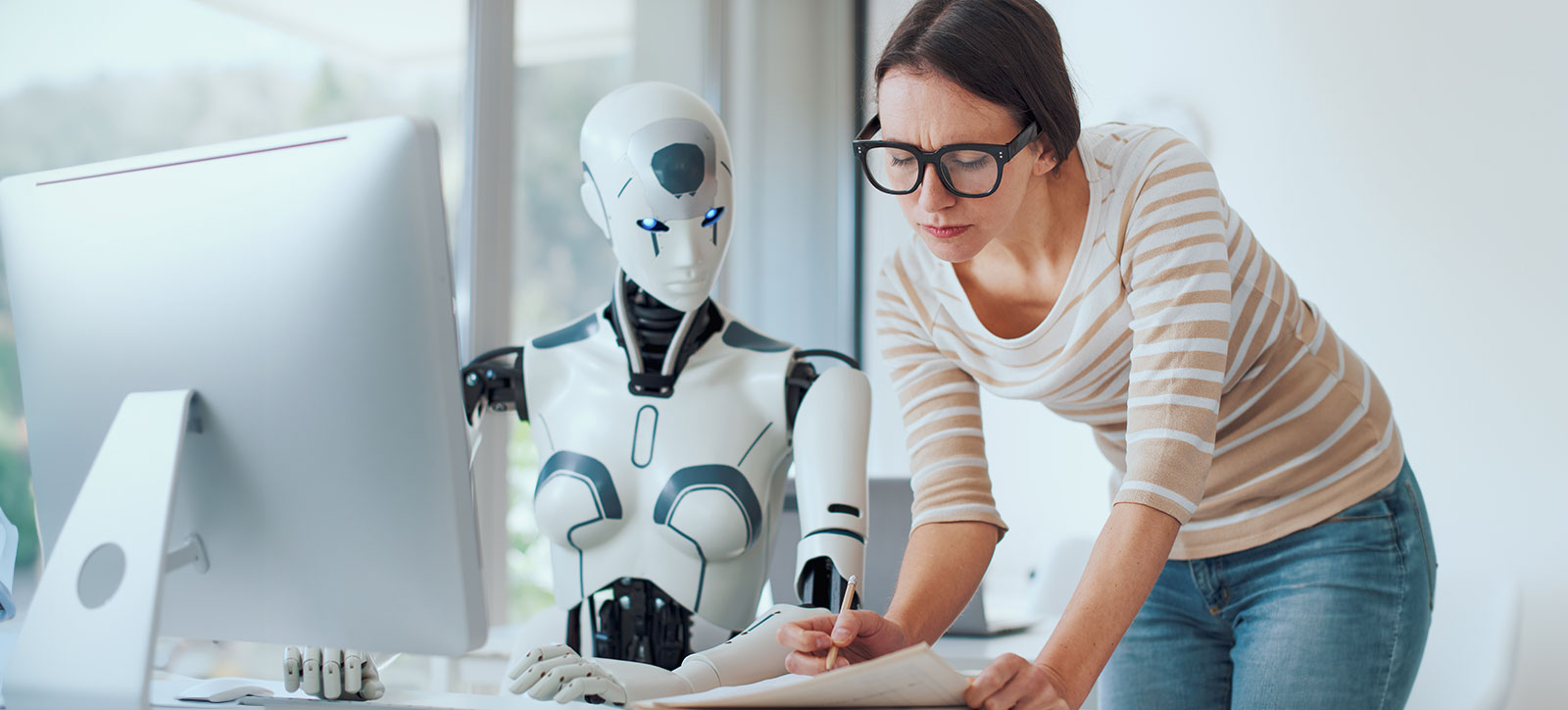 A human employee works with her AI-powered robotic colleague at an office desk, demonstrating the challenges of working with generative AI.