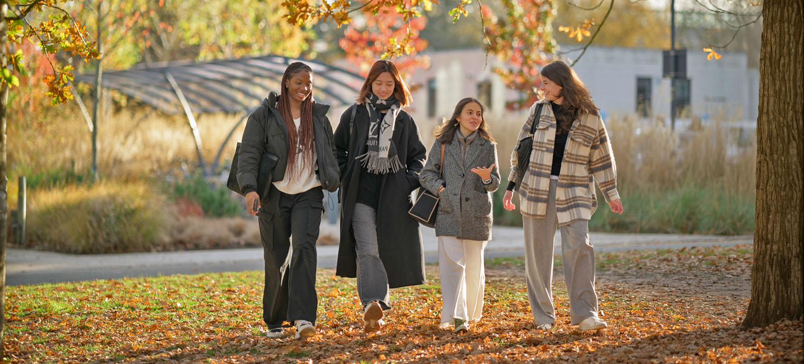 Four undergraduate students walking in the leafy Warwick campus