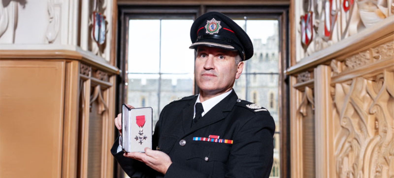 Fire chief Paul Murphy holding his MBE in his uniform