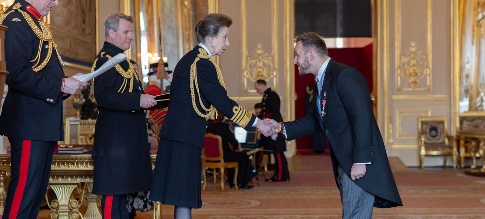 Steven Lynch bowing before Princess Anne as he collects his MBE