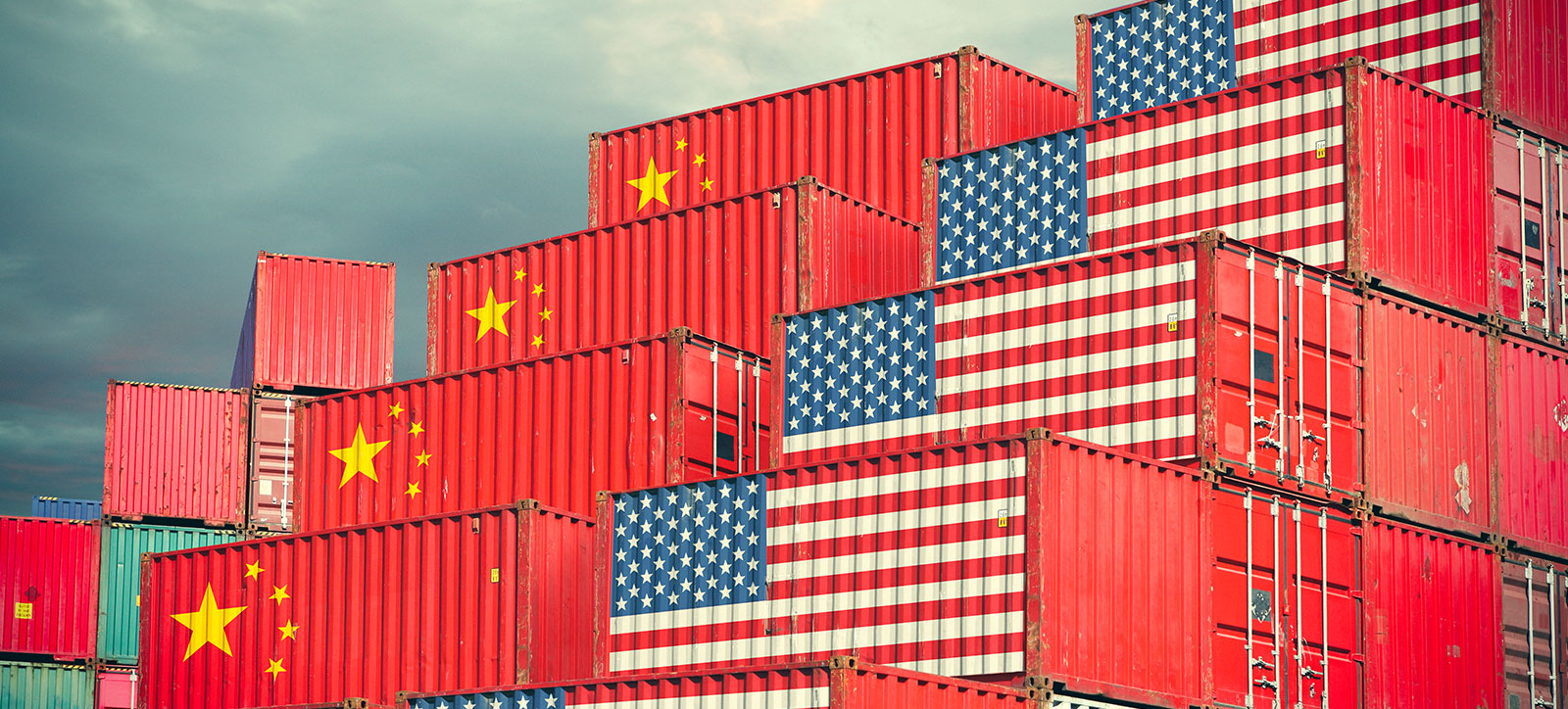 Two stacks of shipping containers. One stack bears the US flag, the other bears the Chinese flag.