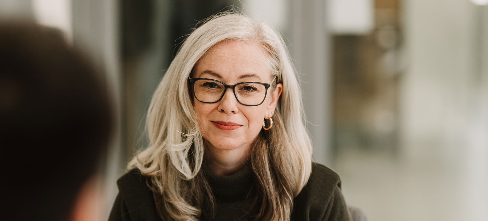 A grey haired woman with glasses studying for the Executive MBA A grey haired woman with glasses studying for the Executive MBA